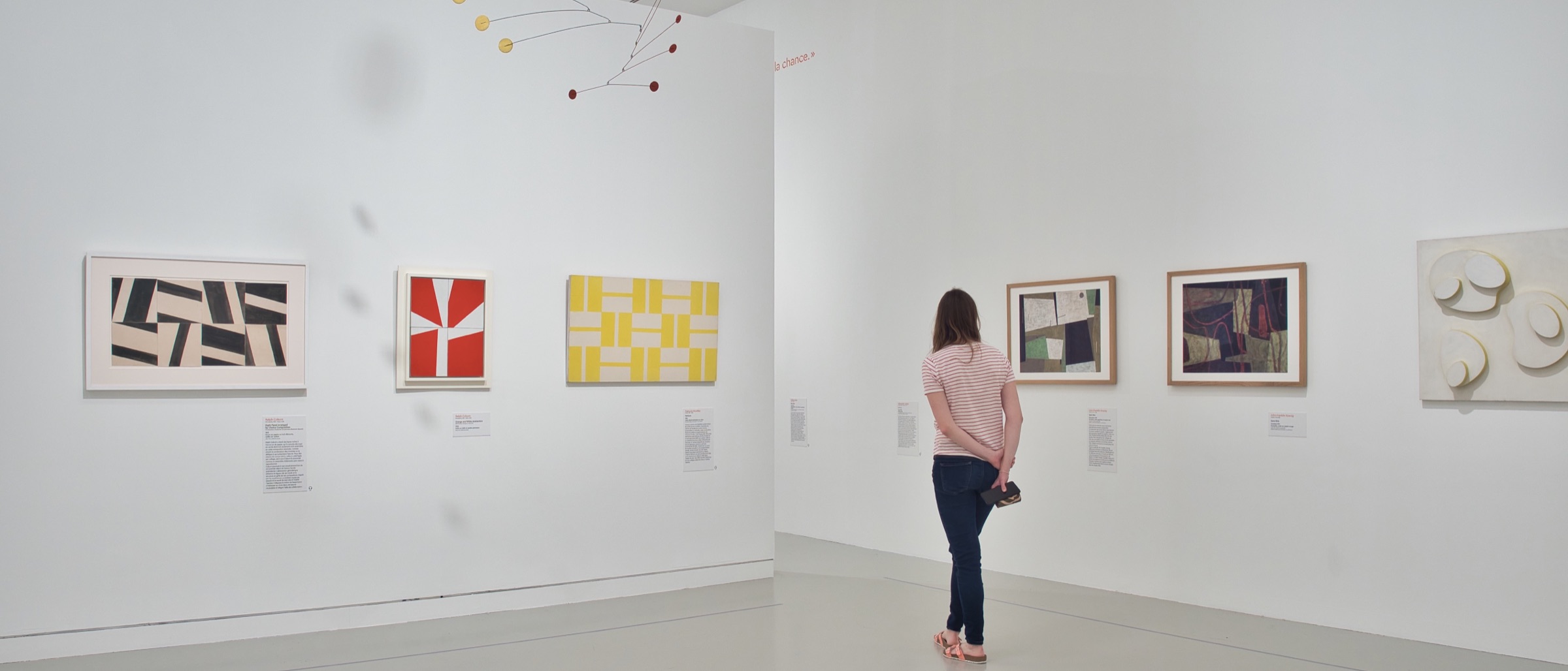 Personne observant des œuvres d'art colorées dans une galerie lumineuse.