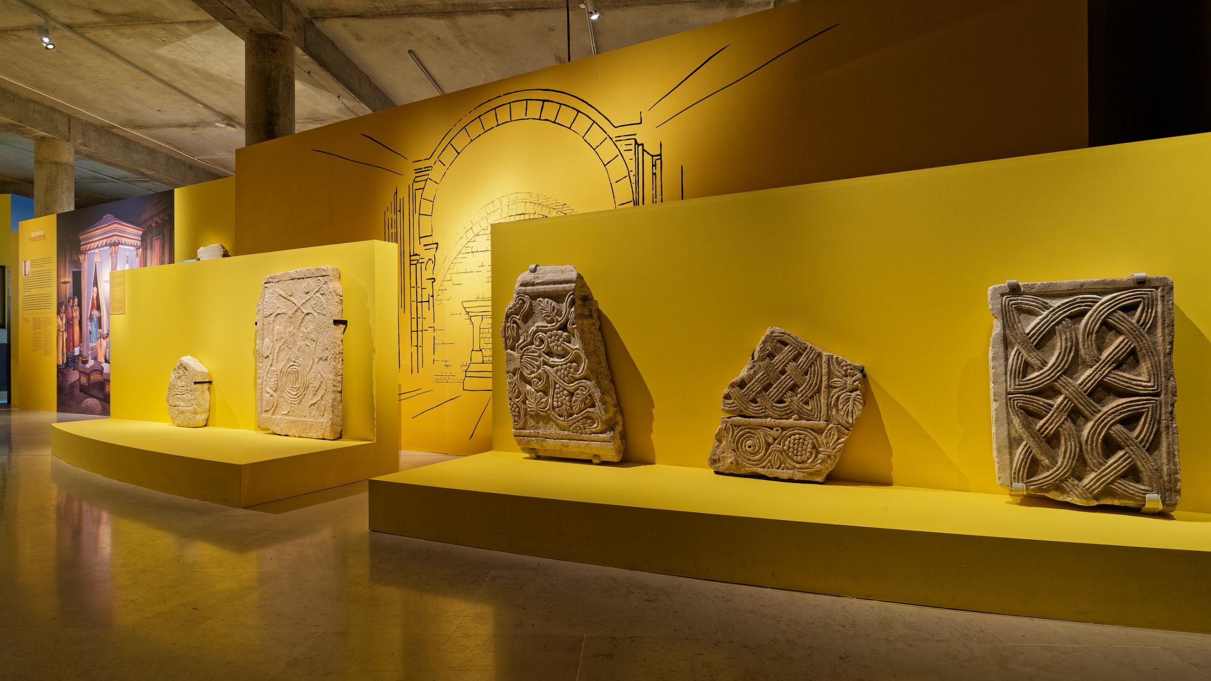 Un mur jaune avec des sculptures en pierre ancienne exposées.