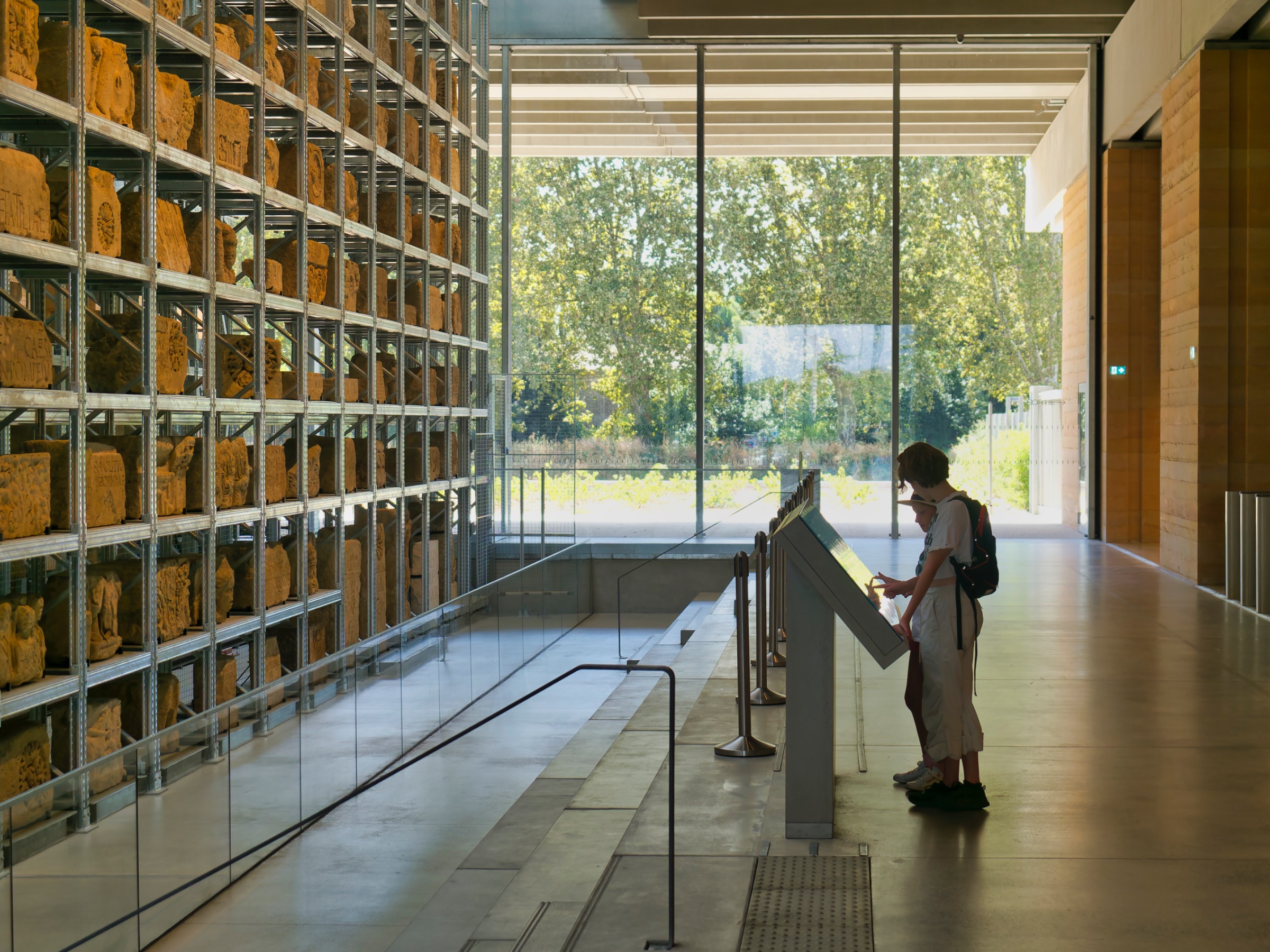 Une femme devant des étagères remplies d'objets dans un espace contemporain et lumineux.