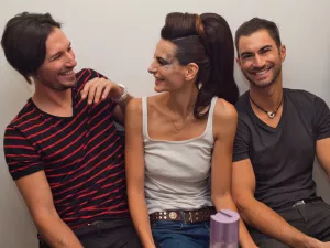 Trois personnes souriantes, assises ensemble, dans une ambiance amicale.