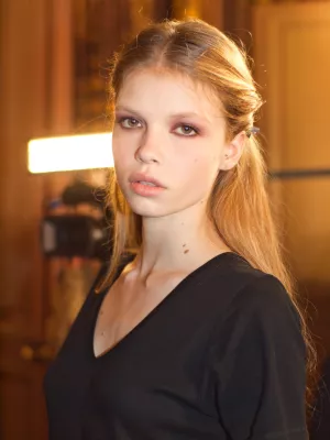 Une jeune femme au regard neutre, cheveux longs et blonds, vêtue d'un t-shirt noir.