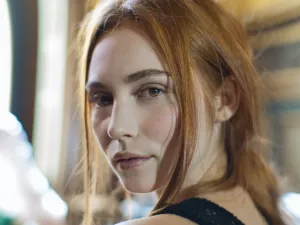 Portrait d'une jeune femme aux cheveux roux, regard intense et doux.