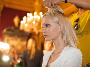 Femme aux cheveux blonds, se faisant coiffer dans un cadre élégant avec de nombreuses lumières.