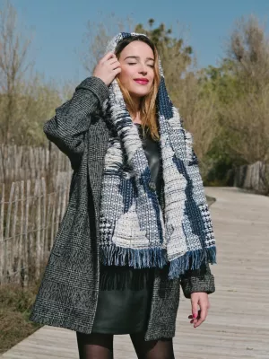 Femme souriante, vêtue d'un manteau et d'un foulard, en pleine nature.