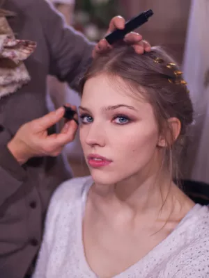 Jeune femme se préparant, maquillée, cheveux ornés de accessoires.