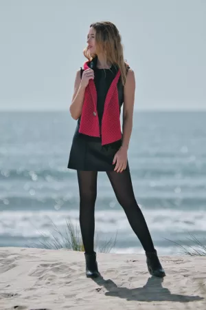 Une femme en robe noire avec un foulard rouge, se tenant sur la plage.