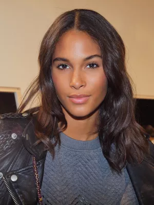 Portrait d'une jeune femme avec des cheveux bruns ondulés et un sourire doux.